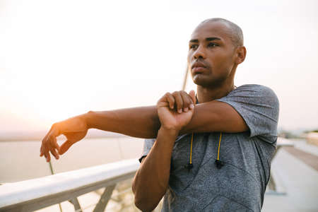 Confident young african sports man stretching on the bridge