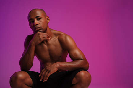 Photo of a handsome serious strong african fitness sports man posing isolated over pink wall backgroundの写真素材