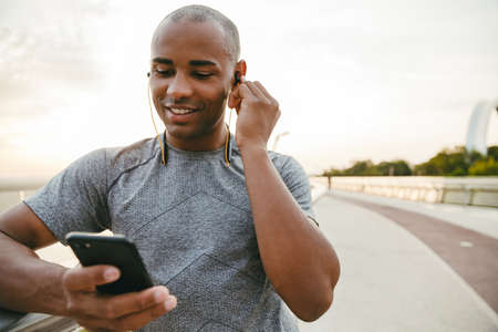 African american athlete man listening to the music and using mobile phone outdoorsの写真素材