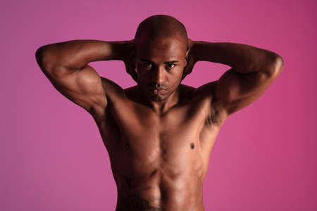 Photo of a handsome african fitness man posing isolated over pink wall background