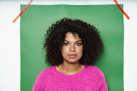 Image of young african american woman posing and looking at camera isolated over multicolored...