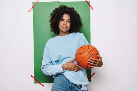 Image of young african american woman posing with basketball isolated over multicolored backgroundの写真素材
