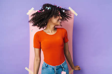 Image of funny african american woman smiling and dancing at camera isolated over multicolored...