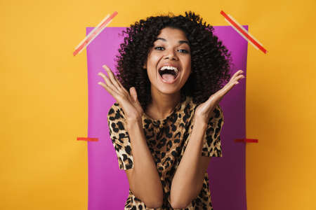 Image of delighted african american woman screaming at camera isolated over multicolored backgroundの写真素材