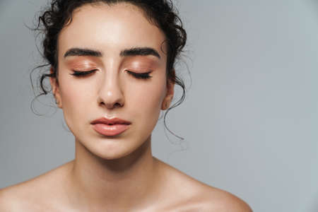 Image of beautiful half-naked woman posing with eyes closed isolated over gray wall