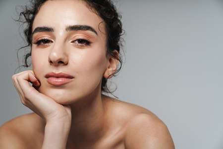 Image of beautiful half-naked woman with curly hair posing and looking at camera isolated over gray wallの写真素材