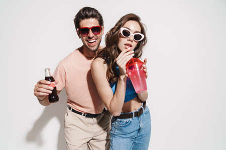 Image of funny beautiful couple dancing while drinking beverages isolated over white backgroundの写真素材