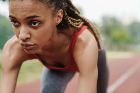 Close up of a fit confident african young woman jogging in the parkの写真素材