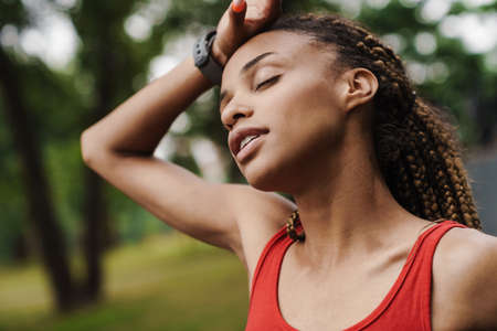 Tired fit young african woman resting after run in the parkの写真素材