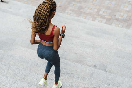 Top view of a fit young sportswoman exercising on stairs outdoors, running