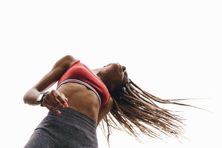 Bottom view of a fit young african sports woman posing with blue sky on a background