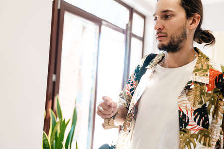 Young man holding house keys standing at the glass doorの写真素材