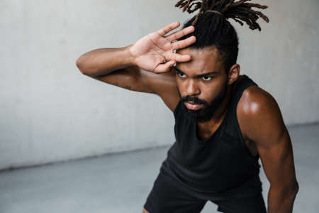 Image of young african american sportsman doing exercise while working out indoors