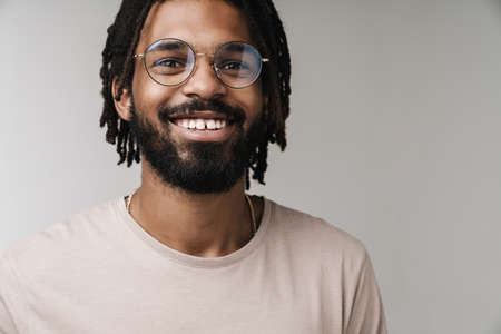 Image of happy positive african guy posing isolated over grey wall background in eyeglasses