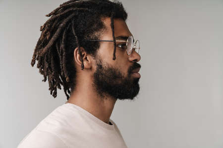 Side view photo of serious african guy posing isolated over grey wall background in eyeglasses