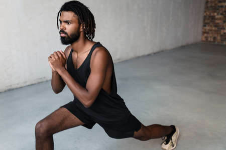 Image of handsome african american sportsman doing exercise while working out indoorsの写真素材