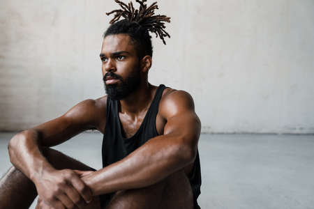Image of young african american sportsman resting while working out indoorsの写真素材