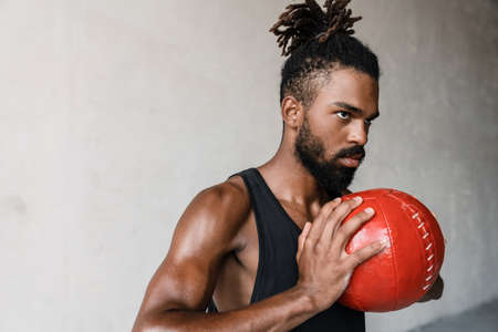 Image of athletic african american sportsman working out with medicine ball indoorsの写真素材