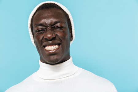 Image of young african american guy in white clothes smiling and looking at camera isolated over...