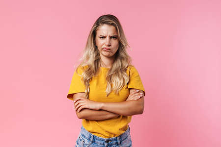 Image of displeased blonde girl posing with hands crossed isolated over pink backgroundの写真素材