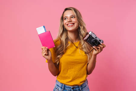 Image of positive happy woman isolated over pink wall background holding passport with tickets and...