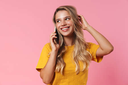 Image of happy young woman isolated over pink wall background talking by mobile phoneの写真素材