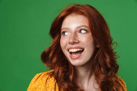 Image of ginger joyful girl laughing and looking aside isolated over green backgroundの写真素材
