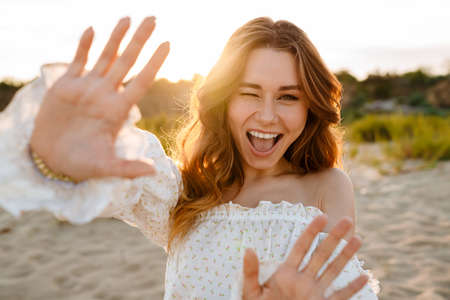 Young caucasian attractive brunette woman smiling and showing her palms at camera outdoorsの写真素材