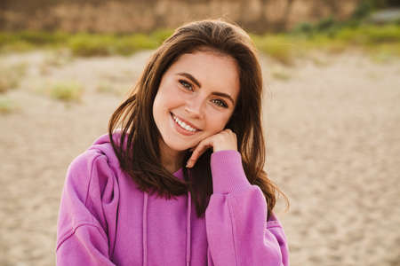 Young caucasian happy woman smiling and looking at camera while walking outdoors