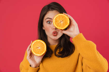 Image of surprised caucasian girl posing with orange isolated over pink backgroundの写真素材