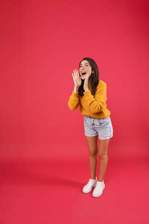 Full length portrait of a happy casual woman screaming away isolated on pink backgroundの写真素材