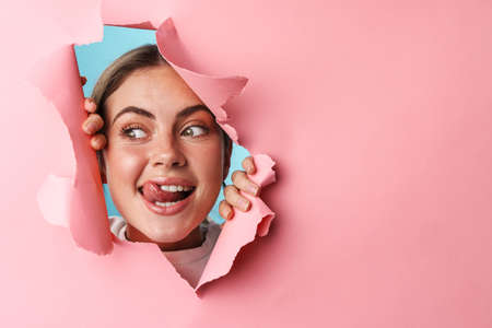 Caucasian young excited woman wondering and looking at copyspace through pink background isolated...