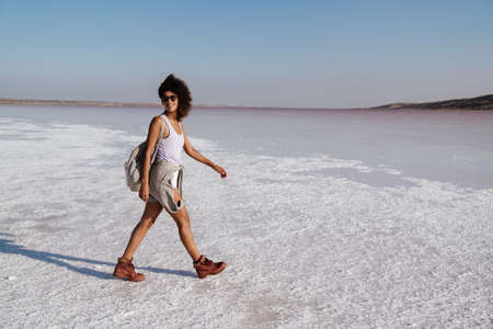 Smiling attractive african woman walking on a salt lake