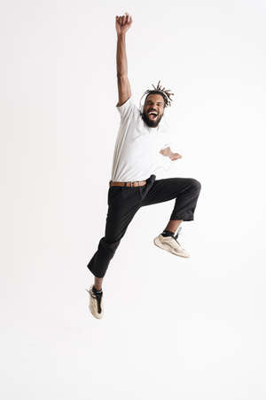 Photo of excited african american guy in headphones jumping while dancing isolated over white backgroundの写真素材