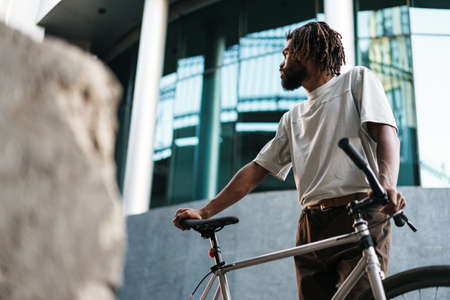 Handsome african american guy posing with bicycle at city street