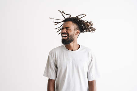 Photo of excited african american guy shaking his dreadlocks isolated over white backgroundの写真素材