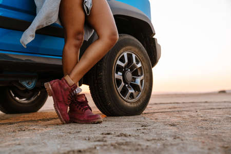 Cropped image of slim african american woman standing near the car while travelling on desertの写真素材