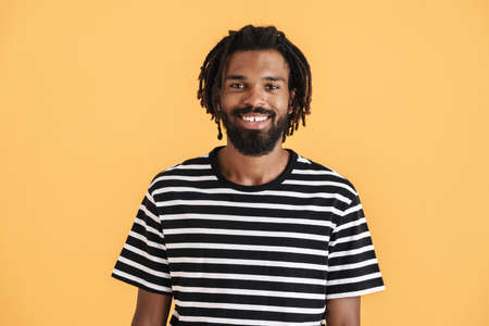 Photo of cheerful african american guy looking and smiling at camera isolated over yellow backgroundの写真素材