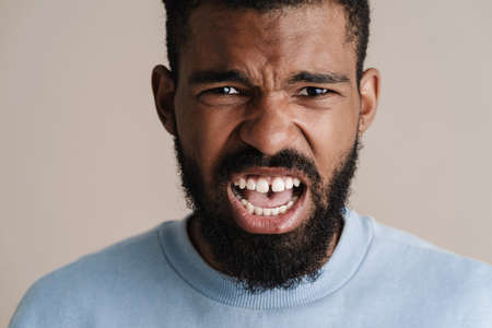 Angry african american guy looking and screaming at camera isolated over white backgroundの写真素材