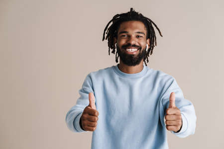 Cheerful african american guy in earphones showing thumbs up isolated over white background