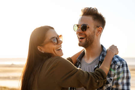 Beautiful happy couple hugging and laughing while strolling on nature at summerの写真素材