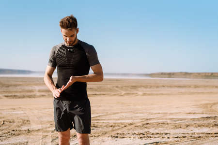 Confident young sportsman standing at the beachの写真素材