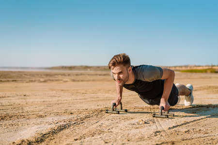 Motivated focused young sportsman exercising at the beach, plank exerciseの写真素材
