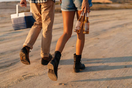 Beautiful young couple strolling with bear and cooler bag on natureの写真素材