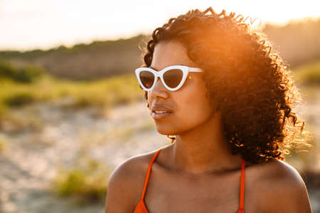 Close up of a young attractive african american woman at the beach, wearing sunglassesの写真素材