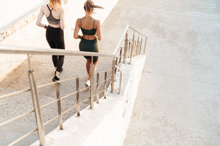 Amazing young fitness sports women friends running outdoors by stepsの写真素材