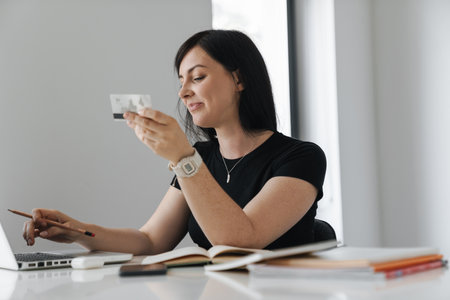 Smiling businesswoman with laptop and credit card in office