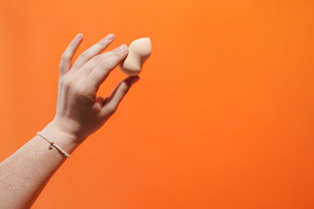 Woman's hand holding beauty sponge isolated on backgroundの写真素材