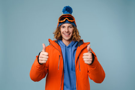 Caucasian joyful sportsman showing thumbs up on camera isolated over blue backgroundの写真素材