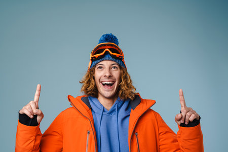 Caucasian excited sportsman pointing fingers and looking upward isolated over blue backgroundの写真素材